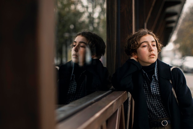 Medium shot non binary person standing next to window