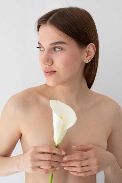 Medium shot nude woman posing with flower