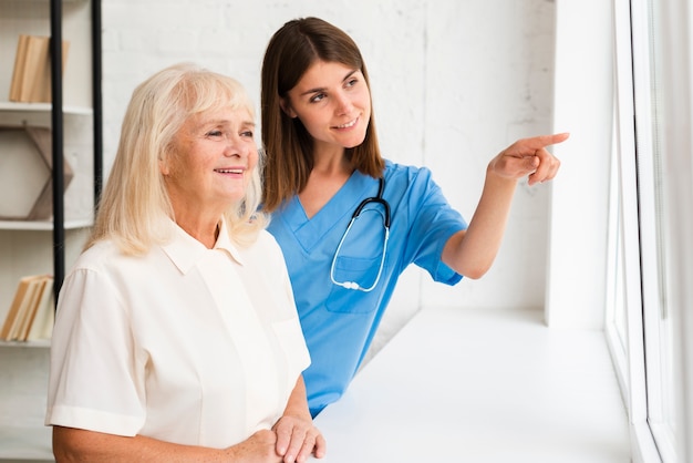 Medium shot nurse pointing to the window