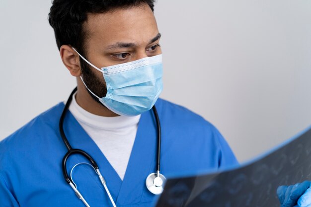 방사선 사진을 보고 있는 마스크를 쓴 중간 샷 간호사