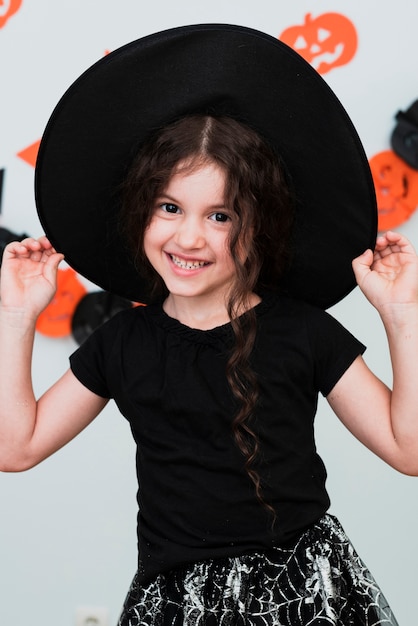 Бесплатное фото Средний снимок милая маленькая девочка в шляпе ведьмы