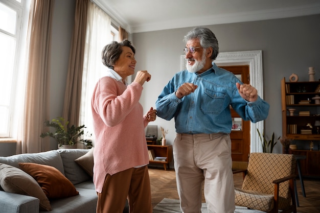 Free photo medium shot old couple dancing at home