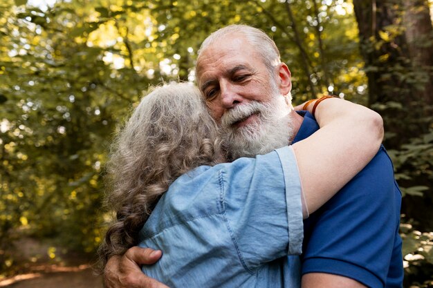 Medium shot old couple hugging in nature