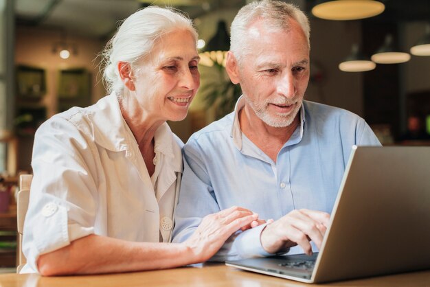 Medium shot old couple using a laptop