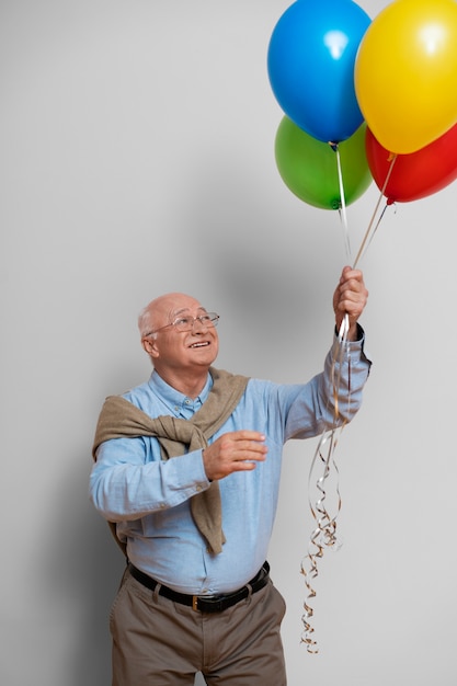 Medium shot old man holding balloons