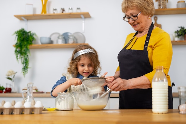 Free photo medium shot old woman and girl in kitchen