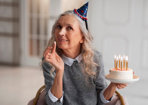 Medium shot old woman holding cake