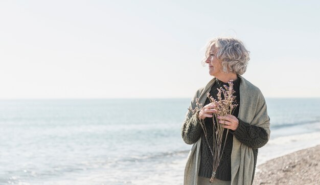 Medium shot old woman holding flowers