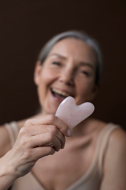 Medium shot old woman holding gua sha