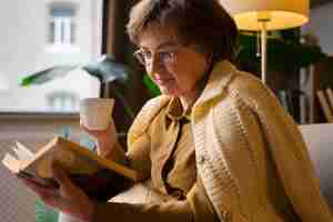 Free photo medium shot old woman reading at home