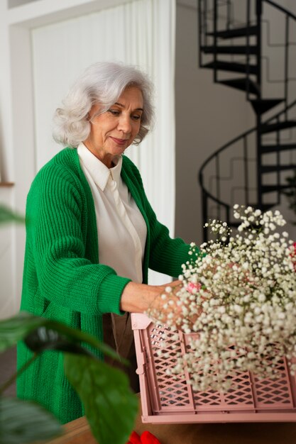 Medium shot old woman taking care of plants