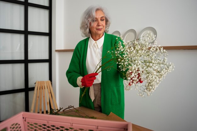 Free photo medium shot old woman taking care of plants