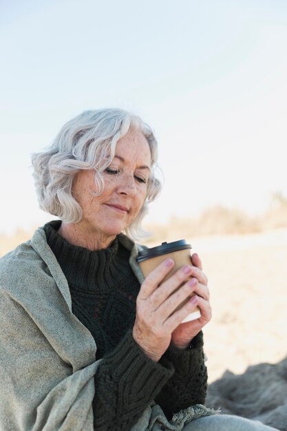 Medium shot old woman with coffee outdoors