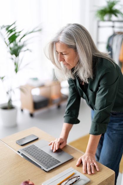 Medium shot old woman working on laptop