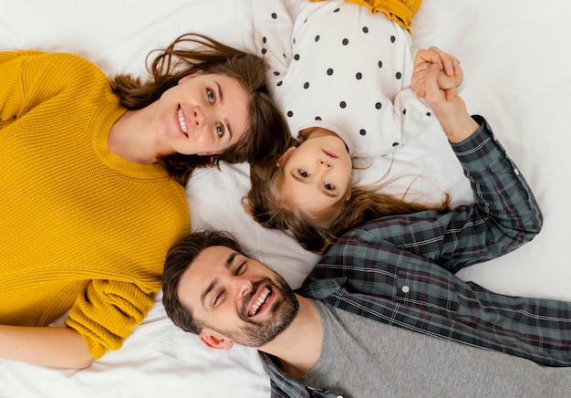 Foto gratuita genitori di tiro medio e bambino a letto distesi