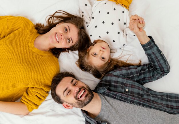 Medium shot parents and kid in bed flat lay