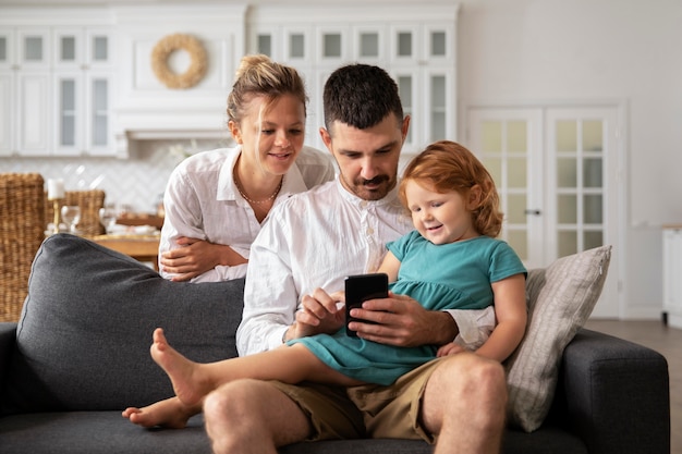 Medium shot parents and kid with device