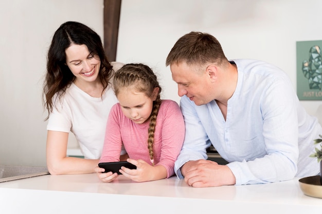 Medium shot parents and kid with phone