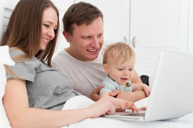 Medium shot parents with kid and laptop