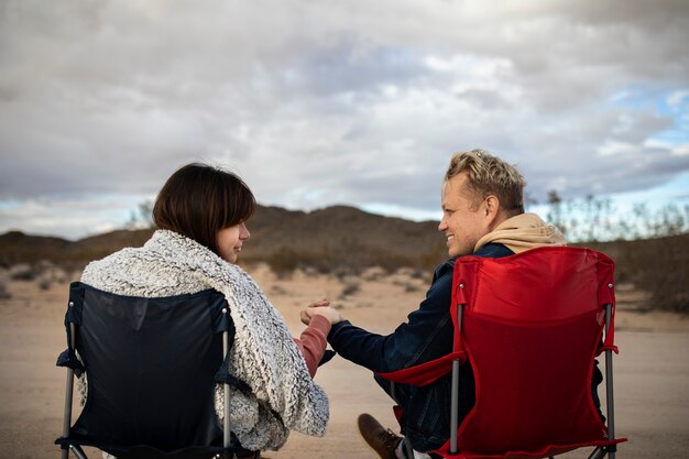 사막의 의자에 앉아 있는 미디엄 샷 파트너