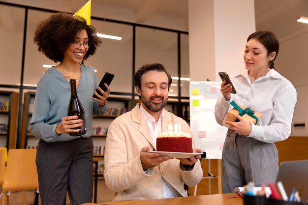 Medium shot people celebrating with cake at work