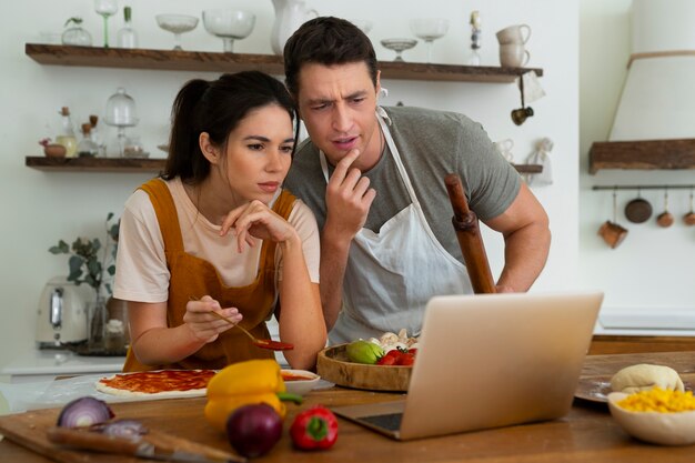 Medium shot people cooking pizza together