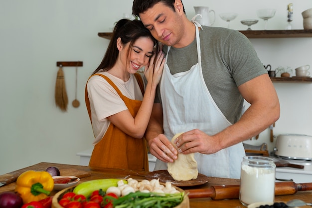 Medium shot people cooking pizza together