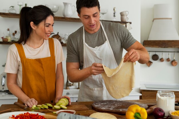 Medium shot people cooking pizza together