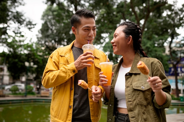 Free photo medium shot people eating corn dog