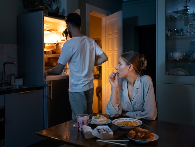 Foto gratuita persone di tiro medio che mangiano spuntini di notte