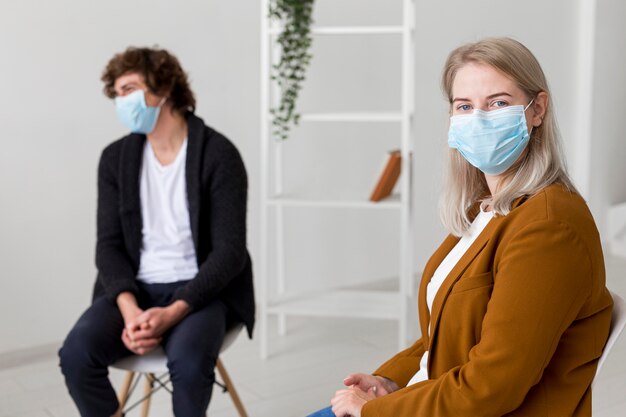 Medium shot people wearing masks indoors