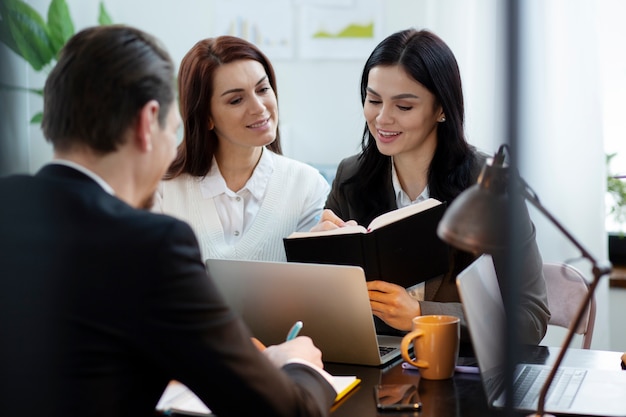 Medium shot people working together at office