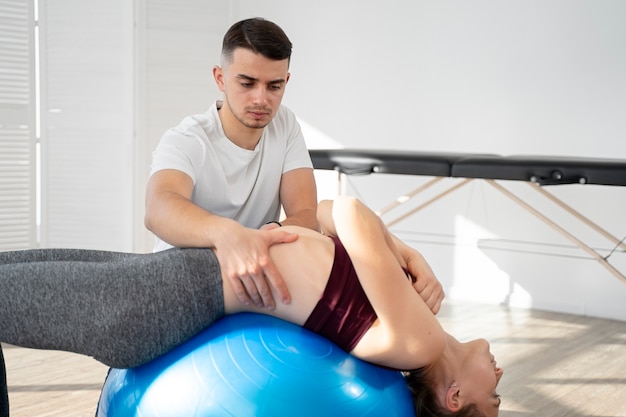 Foto gratuita fisioterapista a colpo medio che aiuta la donna