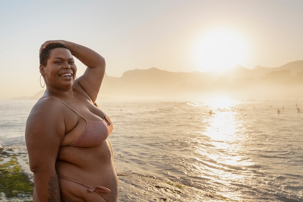 Foto gratuita una donna di taglia media che posa in riva al mare