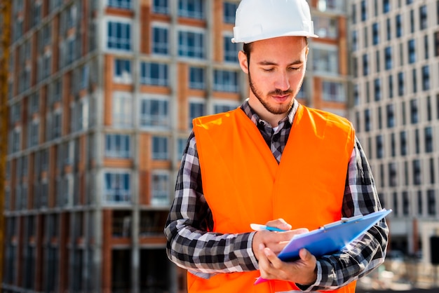 Foto gratuita ritratto del colpo medio della lavagna per appunti della tenuta dell'ingegnere di costruzione