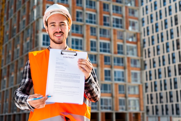 Средний снимок портрет строительного инженера, держащего контракт
