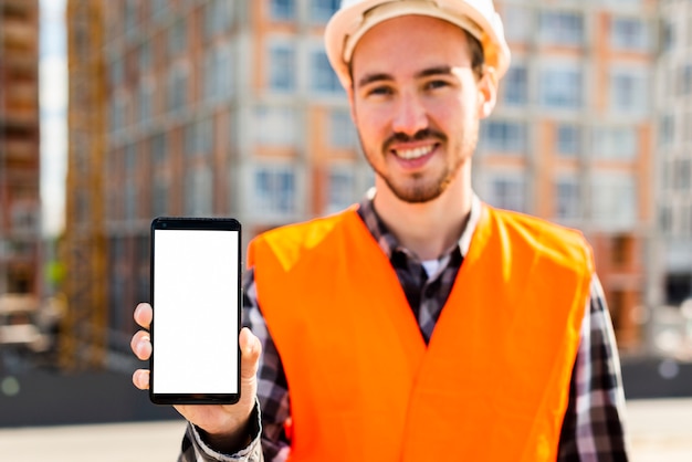 Средний снимок портрет инженер-строитель держит телефон