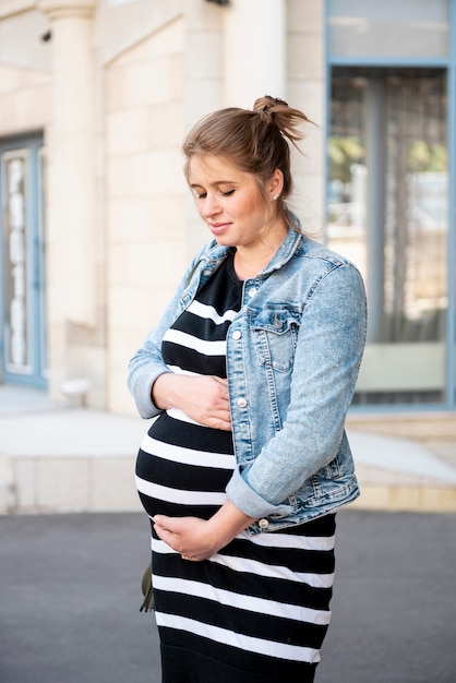 Free photo medium shot pregnant lady posing outdoors