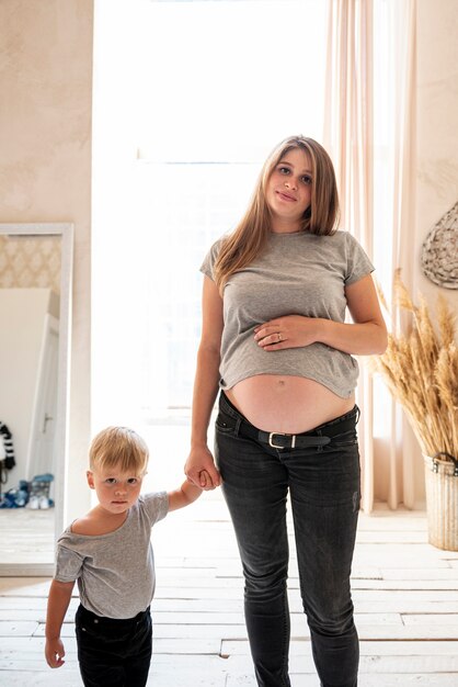 Medium shot pregnant mother posing with son