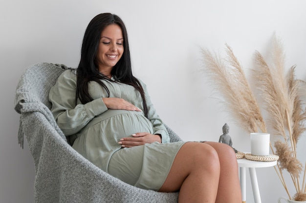 Средний снимок беременной женщины на стуле