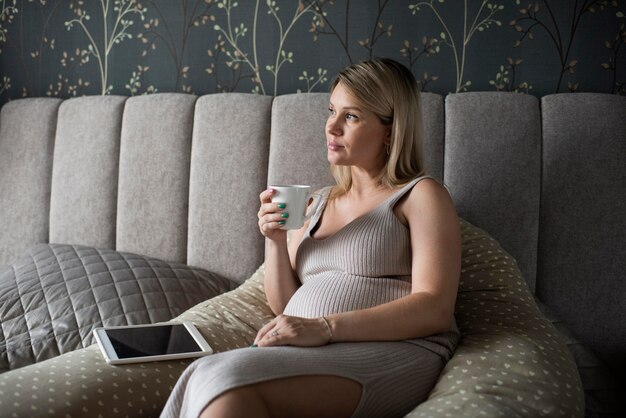 Medium shot pregnant woman holding cup