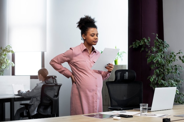 Medium shot pregnant woman holding paper