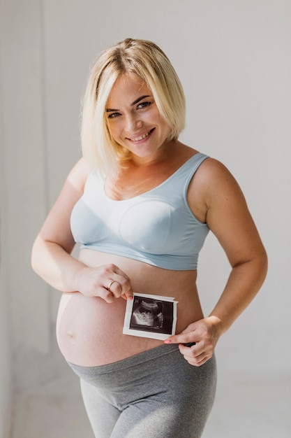 Medium shot pregnant woman holding an ultrasound