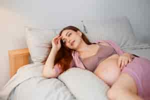 Free photo medium shot pregnant woman laying in bed