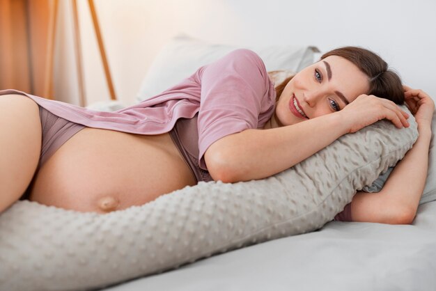 Средний выстрел беременной женщины, лежащей в кровати