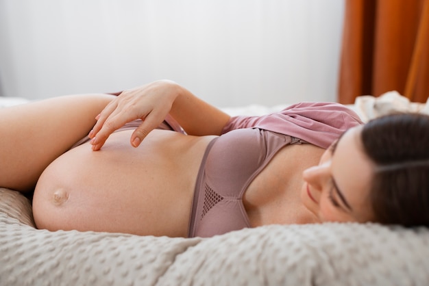 Foto gratuita donna incinta del colpo medio che si situa a letto