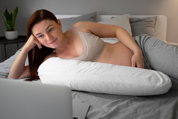 Medium shot pregnant woman laying at home
