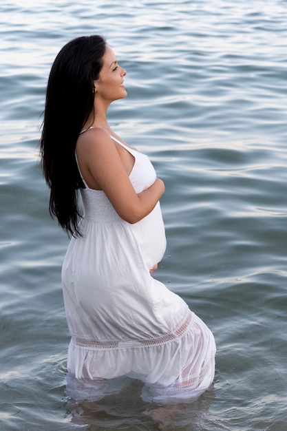 Средний снимок беременной женщины на берегу моря
