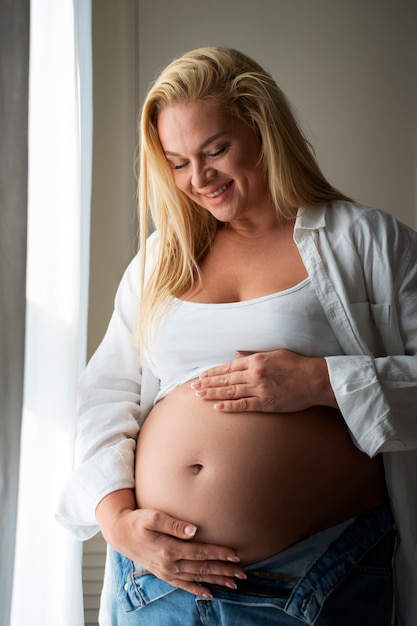 Medium shot pregnant woman spending time indoors