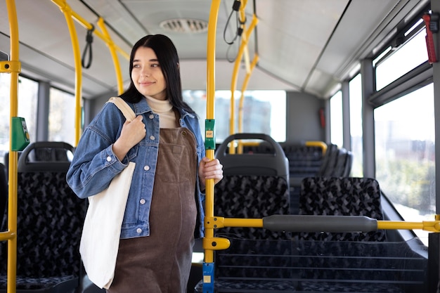 Medium shot pregnant woman traveling by bus